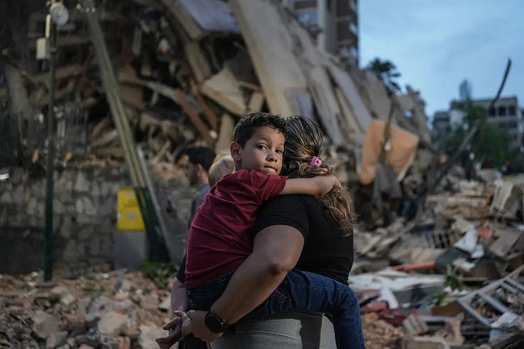 TOPSHOT - Varias personas pasan junto a un edificio derruido tras el terremoto ocurrido en Caracas el 25 de junio de 2026. Dos potentes terremotos consecutivos han causado la muerte de 32 personas y han dejado más de 700 heridos, según declaró el 25 de junio el presidente interino del país, después de que las fuertes sacudidas derrumbaran edificios enteros y provocaran que la gente huyera presa del pánico. (Foto de Manaure QUINTERO / AFP vía Getty Images)