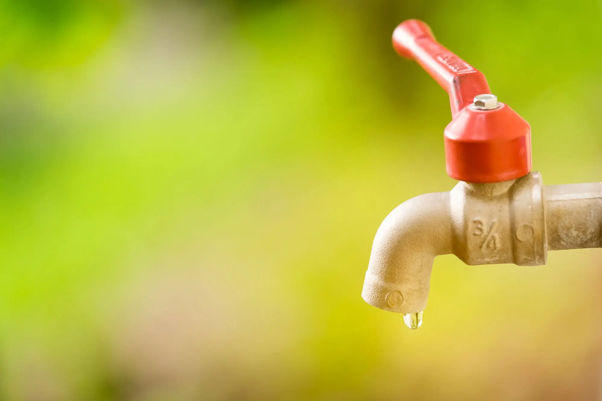 gota-de-agua-de-un-grifo-viejo-sobre-un-bokeh-verde